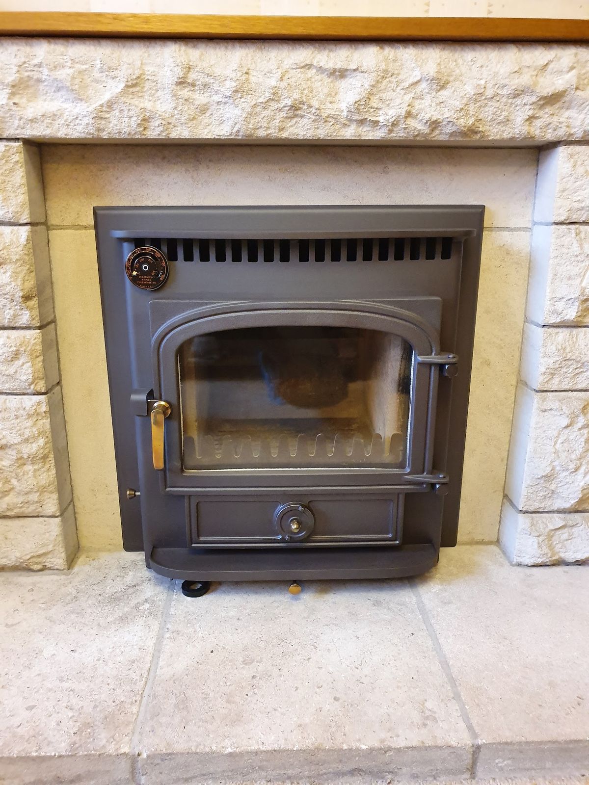 An inset stove in a pale stone fireplace surround