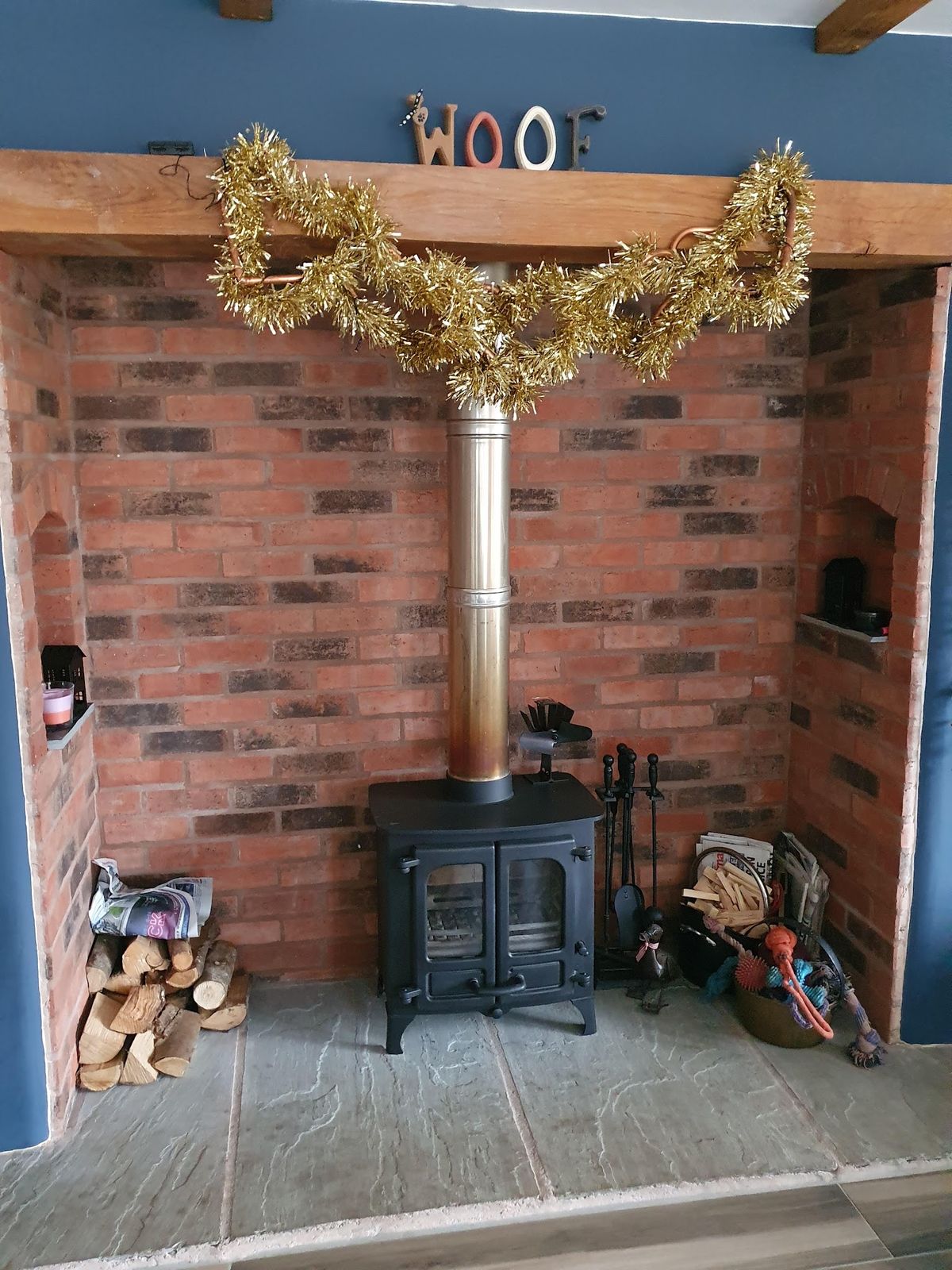 A black stove in a red brick chamber with a tinsel garland