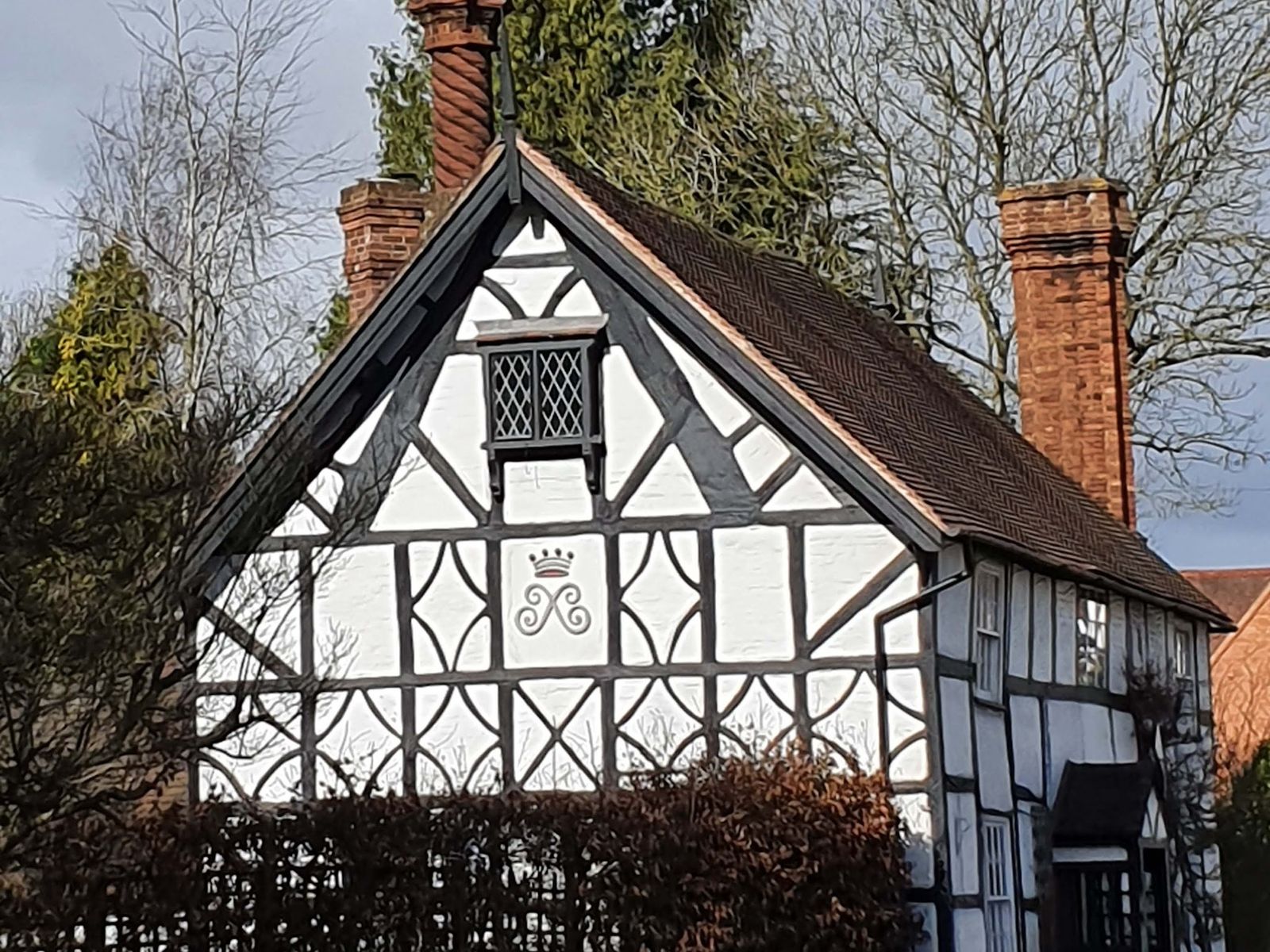 A black and white timber framed house with tall brick chimney stacks
