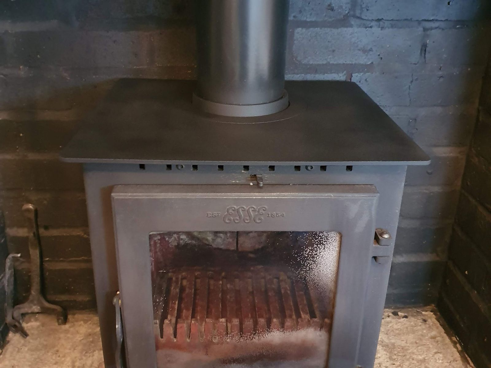 An Esse One stove in a painted brick fireplace
