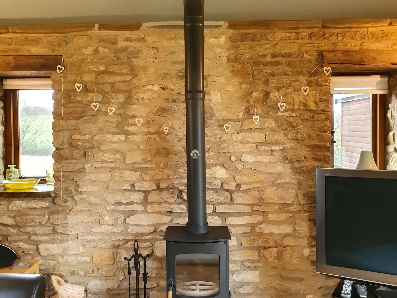 A Charnwood stove against a Cotswold stone wall