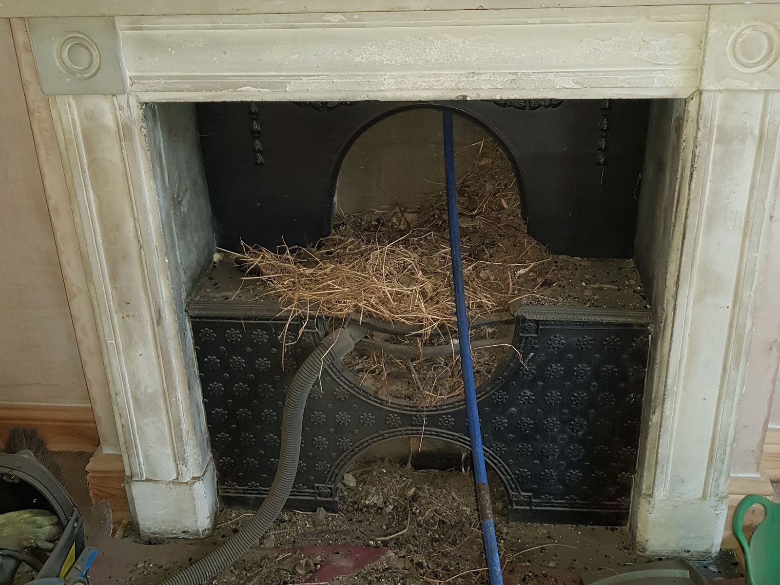 Nesting material piled on a hob grate in a carved stone fireplace