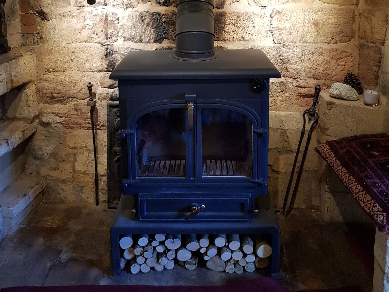 A Clearview 650 with logs stored below, in a stone fireplace